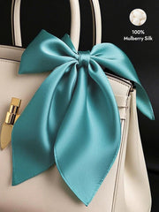 Teal 100% Mulberry Silk Square Scarf tied as a bow on a cream handbag.