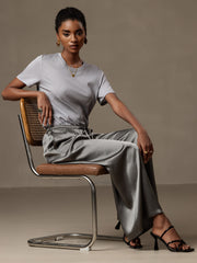 Woman in grey mulberry silk wide-leg pants with elastic waist, paired with a grey top.