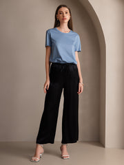Women's black mulberry silk wide-leg pants with elastic waist, paired with a blue silk top.