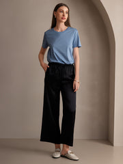 Woman in black mulberry silk wide-leg pants with an elastic waist and a blue t-shirt.