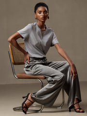 Woman in grey mulberry silk wide-leg pants with elastic waist and matching silk top.