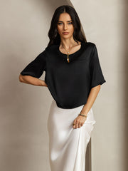 Women's black mulberry silk short sleeve boxy crop top with pocket, styled with a white skirt.