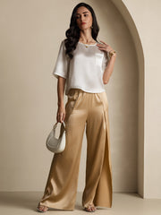 White mulberry silk women's short sleeve boxy crop top with pocket, paired with gold satin wide-leg pants.
