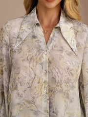 Women's mulberry silk lapel collar blouse with a subtle floral print in soft grey and yellow tones.