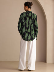 Women's mulberry silk lapel collar blouse in black with green print, paired with white wide-leg pants.