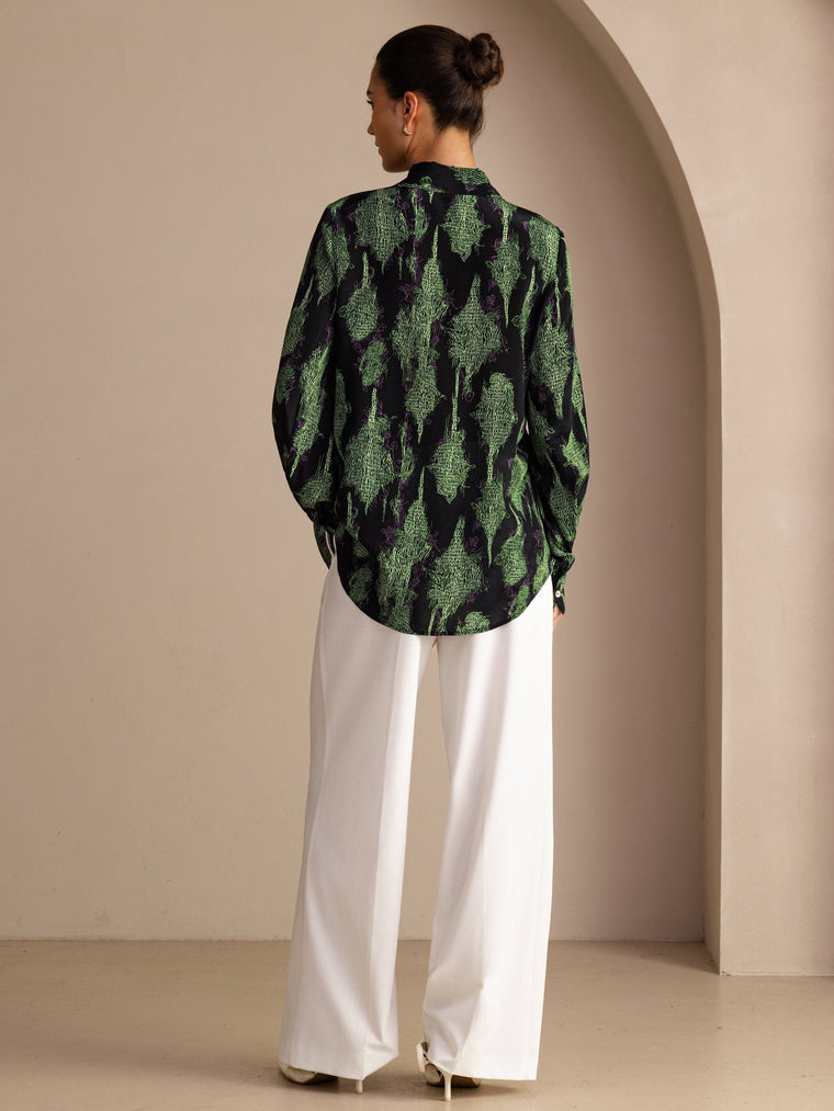Women's mulberry silk lapel collar blouse in black with green print, paired with white wide-leg pants.