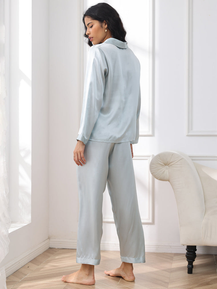Women's light blue mulberry silk long sleeve pajamas set, seen from behind, in a bright room.