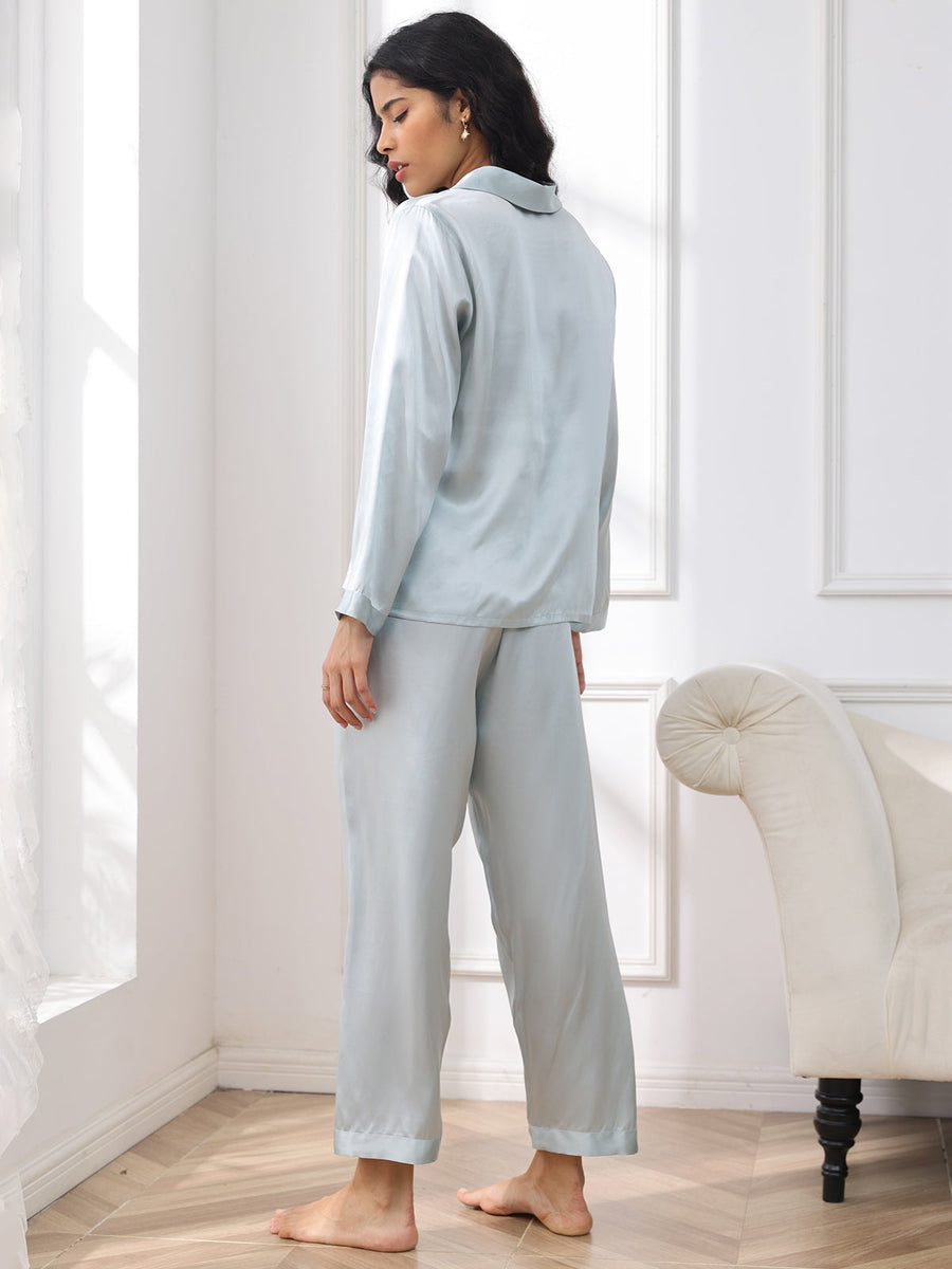 Women's light blue mulberry silk long sleeve pajamas set, seen from behind, in a bright room.