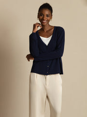 Women's navy mulberry silk V-neck long sleeve cardigan over a white top, paired with cream trousers.