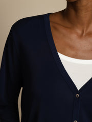 Women's navy blue mulberry silk V-neck long sleeve cardigan with buttons over a white top.