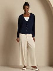 Women's navy mulberry silk V-neck long sleeve basic cardigan over a white top and cream wide-leg pants.