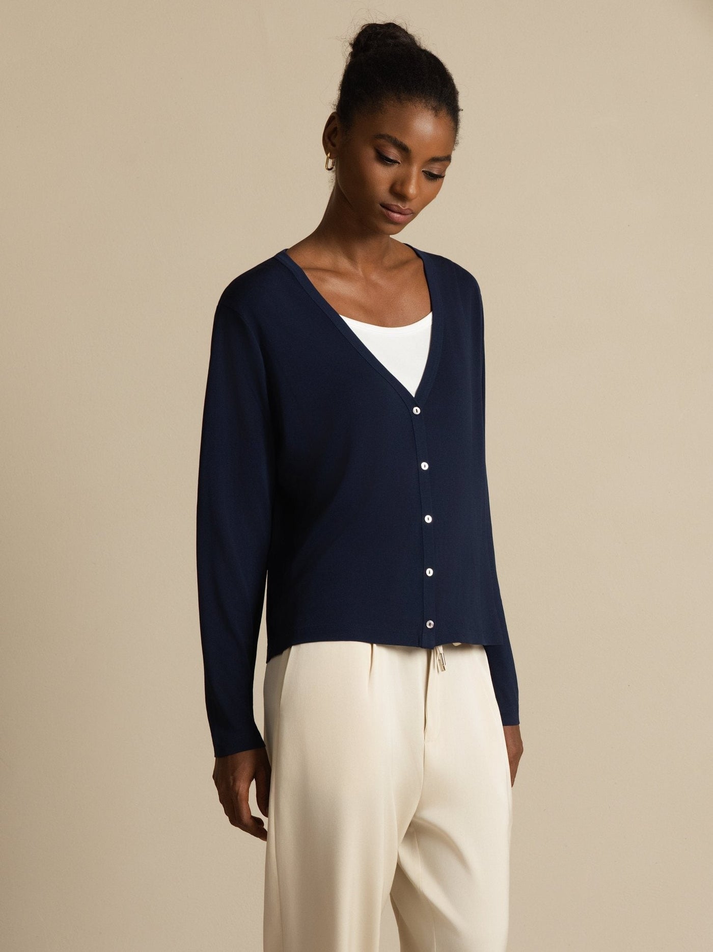 Women's dark blue mulberry silk V-neck long sleeve cardigan with white buttons, worn over a white top.