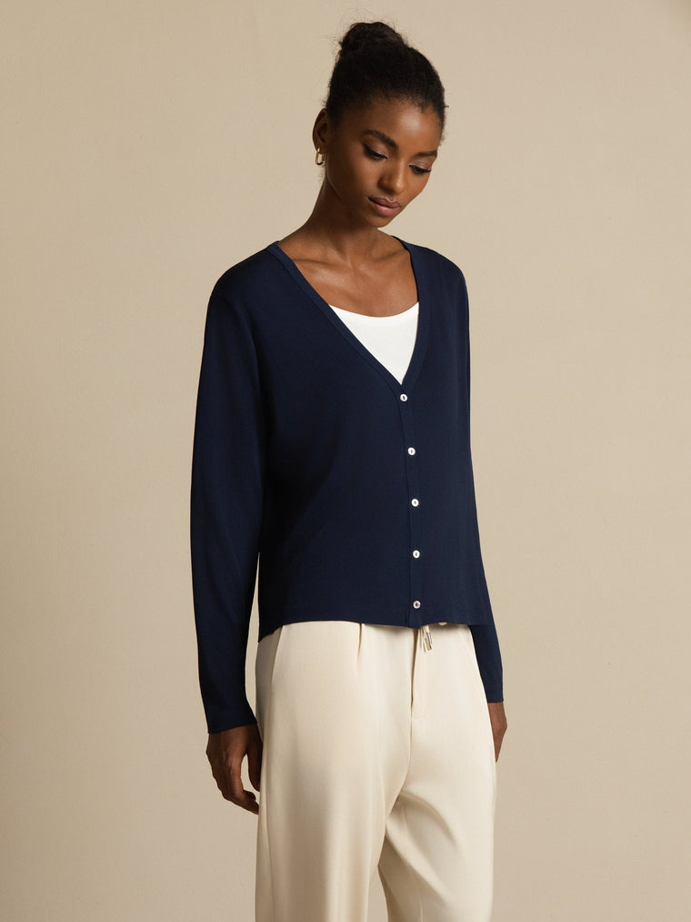 Women's dark blue mulberry silk V-neck long sleeve cardigan with white buttons, worn over a white top.