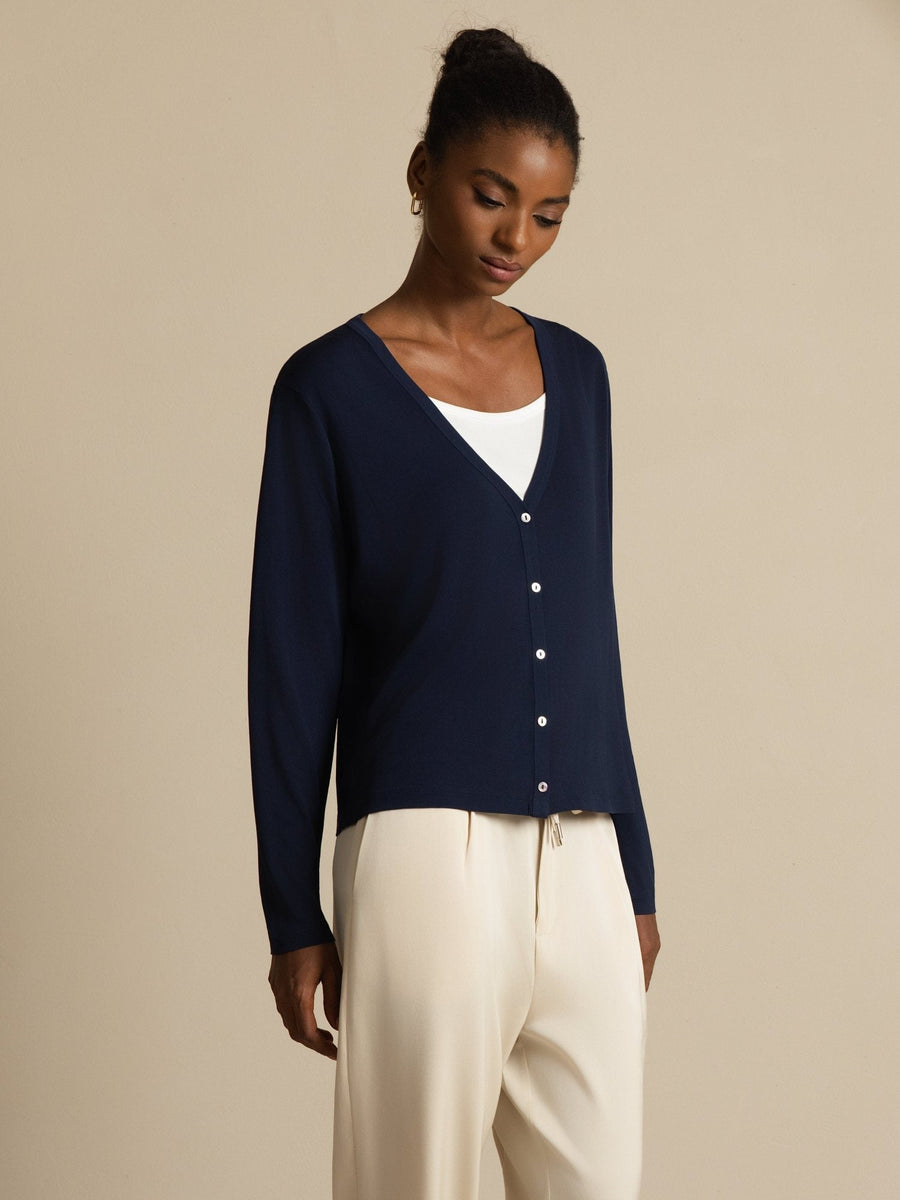 Women's dark blue mulberry silk V-neck long sleeve cardigan with white buttons, worn over a white top.