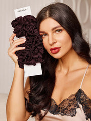 Woman holding a bundle of dark brown pure silk scrunchies, 2cm, with a classic ruffled design.