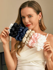 Woman holding a bundle of 5 pure mulberry silk scrunchies in black, navy, champagne, pink, and white.