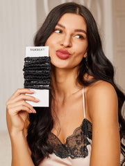 Woman holding a bundle of 10 black pure silk skinny hair scrunchies, 1cm wide.