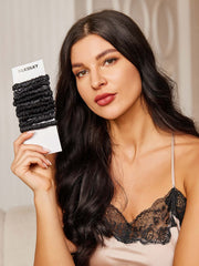Woman holding 10 black pure silk skinny hair scrunchies, 1cm wide.