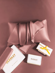 Rose gold 19 Momme mulberry silk pillowcase with hidden zipper, folded on a matching silk sheet.