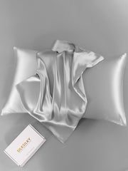 Silver 19 Momme 100% Mulberry silk pillowcase with a hidden zipper, folded on a gray background.