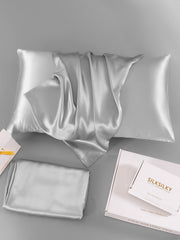 Silver 19 Momme 100% Mulberry Silk Pillowcase with hidden zipper, folded on a gray surface with packaging.