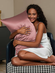 Smiling woman hugging a pink 19 Momme mulberry silk pillowcase with a hidden zipper.