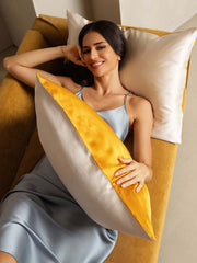 Woman relaxing on a sofa with a two-tone mulberry silk pillowcase in gold and light gray.