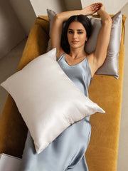 Woman on a mustard sofa with a two-tone mulberry silk pillowcase: white front, silver back.