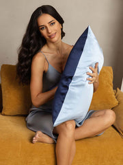 Two-tone mulberry silk pillowcase in dark blue and light blue, held by a woman.