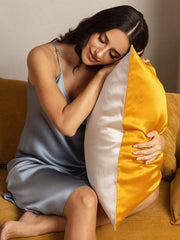 Two-tone mulberry silk pillowcase in gold and light beige, held by a woman in a silk slip.