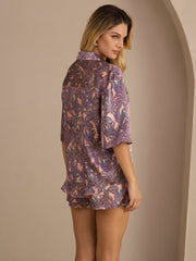 Women's pink mulberry silk pajama set with palm tree print, short sleeve button-up top and shorts.