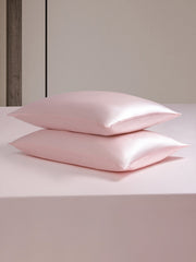 Two stacked pink 19 Momme mulberry silk pillowcases on a matching silk duvet cover.