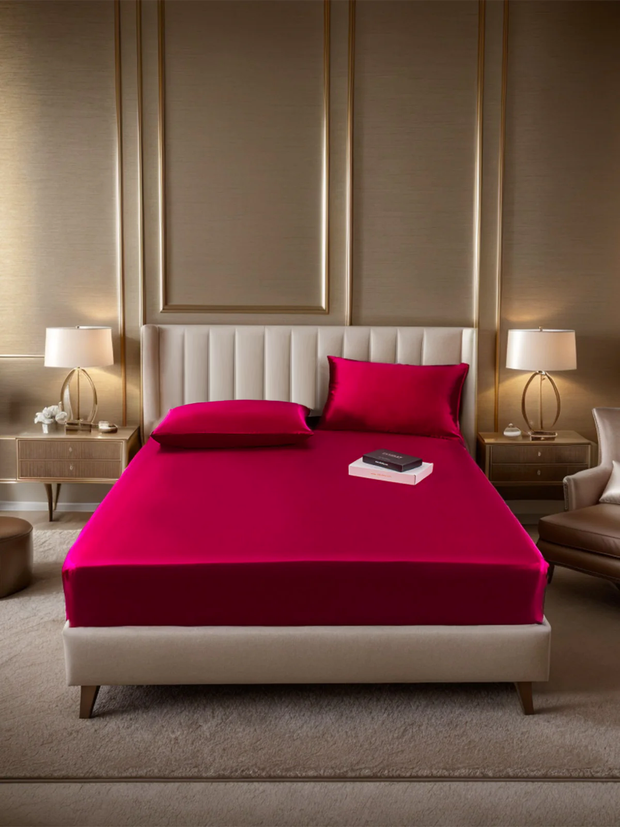 Luxurious Marberry 19 Momme silk fitted sheet and two pillowcases in vibrant fuchsia on a modern bed.