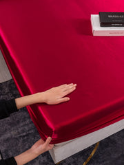 Marberry red 19Momme silk fitted sheet with a hand adjusting it, and a product box on the bed.