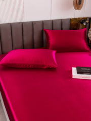 Vibrant magenta 19 Momme mulberry silk fitted sheet and two pillowcases on a bed.