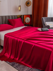 Vibrant red 19 Momme mulberry silk flat sheet and two pillowcases on a bed.
