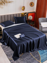 Dark blue 19 Momme mulberry silk flat sheet and two pillowcases on a bed.