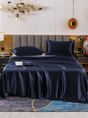 Navy 19 Momme mulberry silk flat sheet and two pillowcases on a bed.