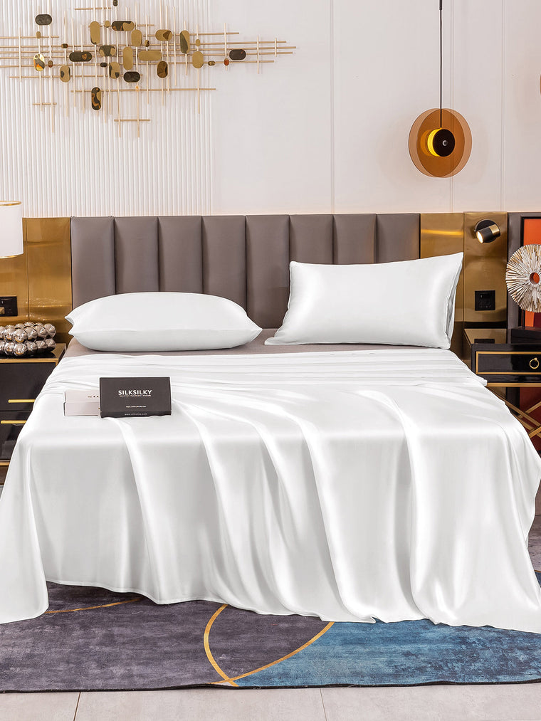 White 19 Momme mulberry silk flat sheet and two pillowcases on a bed.