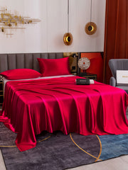 Vibrant red 19 Momme mulberry silk flat sheet and two pillowcases on a bed.