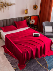 Luxurious red 19 Momme mulberry silk flat sheet and two pillowcases on a bed.