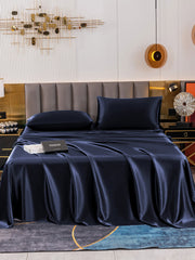 Navy blue 19 Momme mulberry silk bedding set with fitted sheet, flat sheet, and two pillowcases on a bed.