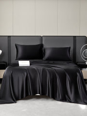 Black 19 Momme mulberry silk bedding set with fitted sheet, flat sheet, and two pillowcases on a modern bed.
