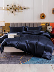 Dark blue 19Momme mulberry silk duvet cover set with fitted sheet and two pillowcases on a bed.