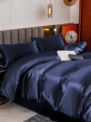 Luxurious navy blue 19 Momme mulberry silk duvet cover set with flat sheet and two pillowcases on a bed.