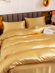 Golden 19Momme mulberry silk duvet cover set with flat sheet and two pillowcases on a bed.