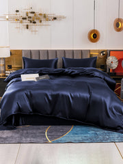 Luxurious navy blue 19 Momme mulberry silk duvet cover set with flat sheet and two pillowcases on a modern bed.