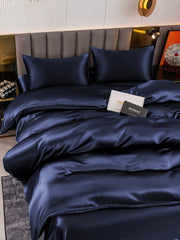 Navy blue 19 Momme mulberry silk duvet cover set with flat sheet and two pillowcases on a bed.