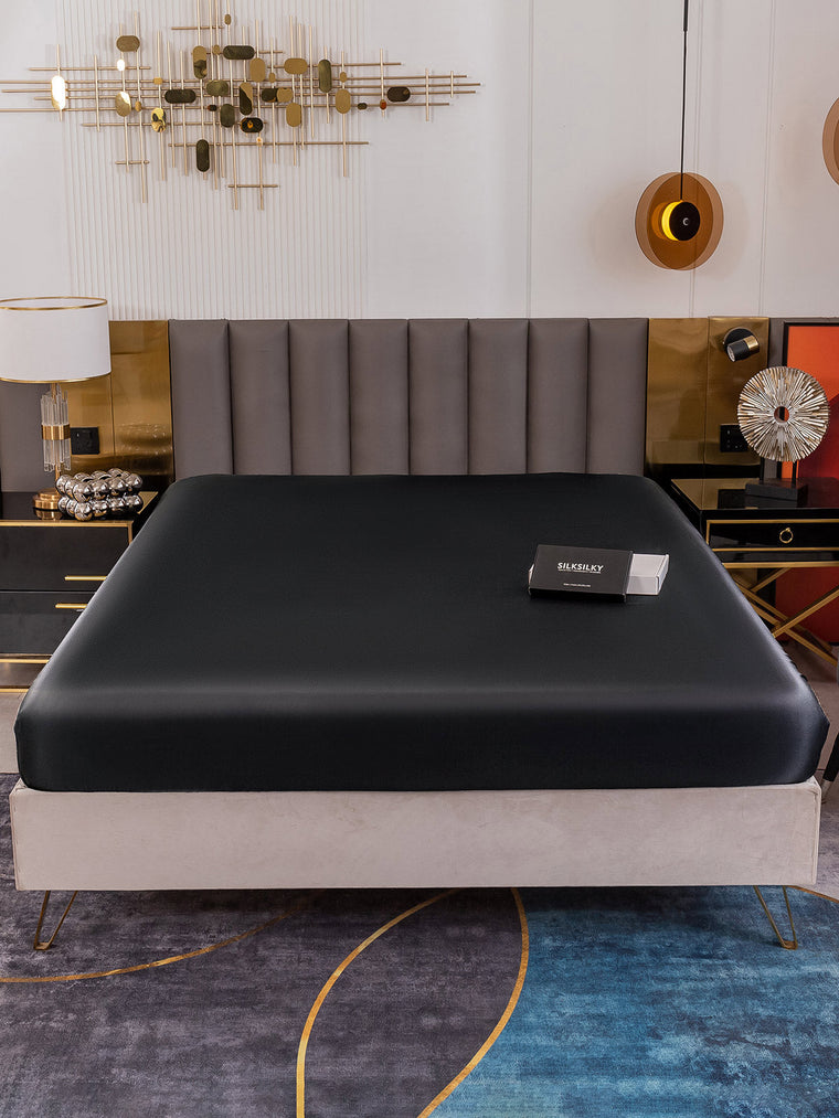 Black 19 Momme Mulberry Silk Seamless Fitted Sheet on a bed, showcasing its smooth, luxurious texture.