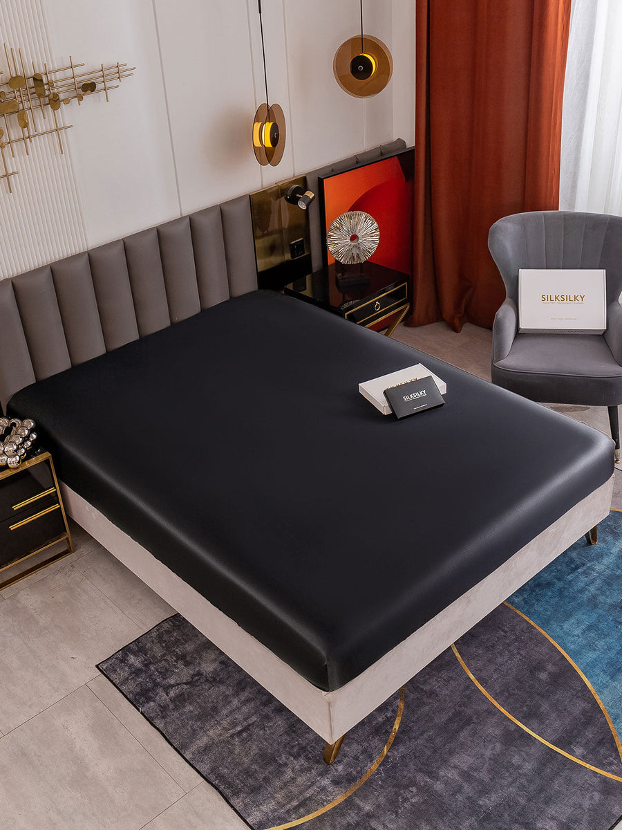 Black 19Momme Mulberry Silk Seamless Fitted Sheet on a bed in a modern bedroom setting.